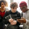 A diverse group of young friends interacting with a cellphone indoors