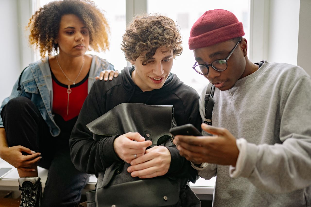 A diverse group of young friends interacting with a cellphone indoors