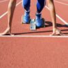 A college athlete, frozen at the start line, waiting to start a race at the track field.