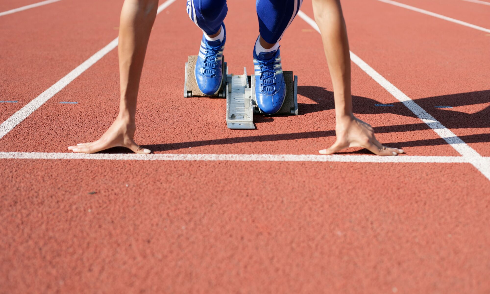 A college athlete, frozen at the start line, waiting to start a race at the track field.