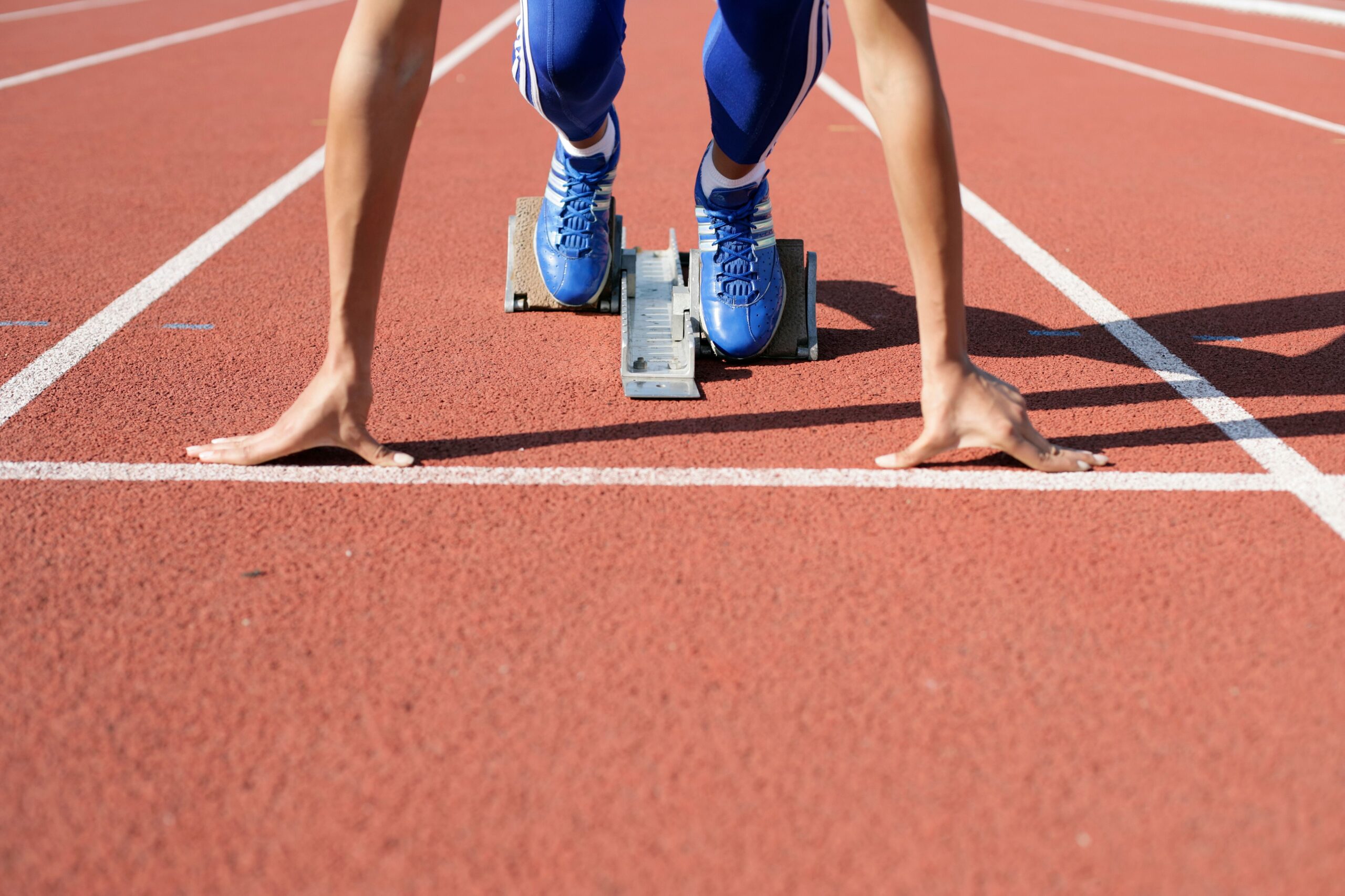 A college athlete, frozen at the start line, waiting to start a race at the track field.